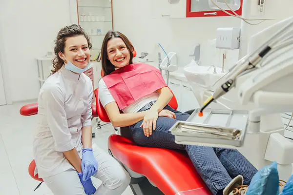 A dentist smiling brightly with her seated patient, suggesting a comfortable dental care visit.